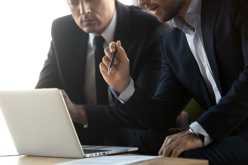 ビジネスマンがPCを見ながら相談している様子の画像